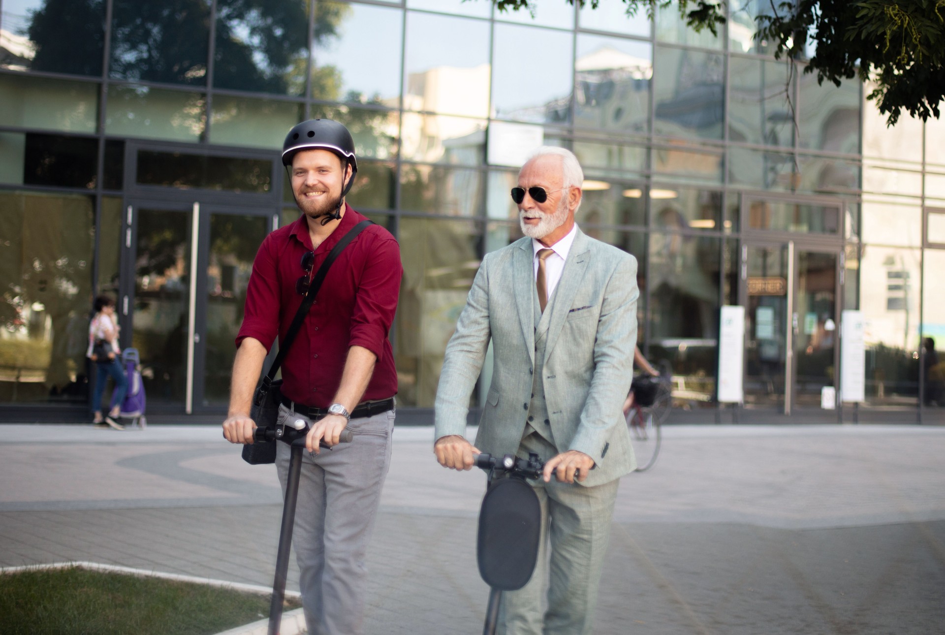 Two business men riding electric scooter in the city.